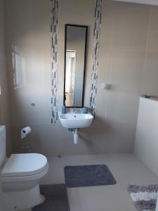 a white bathroom with a toilet and a sink at Sunrise Villa Self Catering and Accommodation in Lüderitz