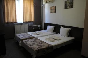 two beds in a hotel room with towels on them at Guest House Lazur in Burgas