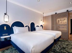 two beds in a room with blue walls at Doubletree By Hilton Nice Centre Iconic in Nice