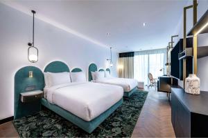 a hotel room with two beds and a desk at Doubletree By Hilton Nice Centre Iconic in Nice