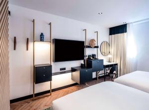 a hotel room with a television and a desk at Doubletree By Hilton Nice Centre Iconic in Nice