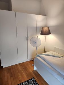 ミュンヘンにあるMyRoom - Munich Fair Apartmentsの白いキャビネット、ベッド、ランプが備わるベッドルーム1室が備わります。