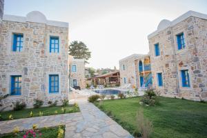 a large stone building with blue windows and a yard at LA Petra Boutique HOTEL in Datca