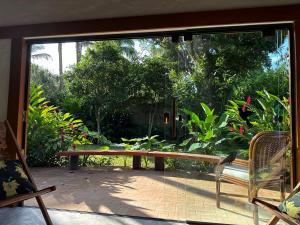 eine überdachte Veranda mit einer Holzbank und einem Fenster in der Unterkunft Vila dos Tangarás, Casa 2 Boutique Riacho - 30m do mar in Toque Toque Grande + 85 Fotos