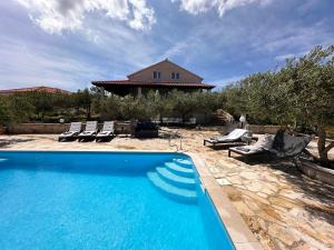 a swimming pool with chairs and a house at Villa Belvedere Žiža in Donji Humac