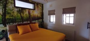 a bedroom with a yellow bed with two windows at Bed & Breakfast Appenseweg in Voorst