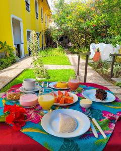 a table with plates of food and glasses of orange juice at Aguamarinha Pousada in Porto De Galinhas