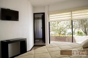um quarto com uma cama, uma televisão e uma janela em Hotel Bellavista Quito em Quito