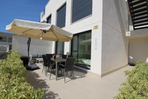 taras ze stołem, krzesłami i parasolem w obiekcie Villa Tindra w mieście Torrevieja
