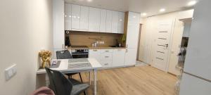 a kitchen with white cabinets and a table and chairs at Kaštonų pavėsis in Marijampolė