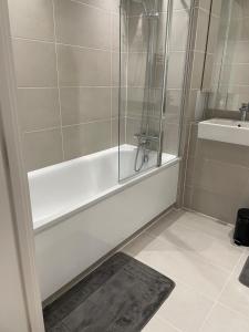 a bathroom with a shower and a tub and a sink at Royal One Bed Apartment in North Woolwich