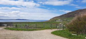 a dirt road with a fence and a view of the ocean at Sea View Cottage in Clonmany