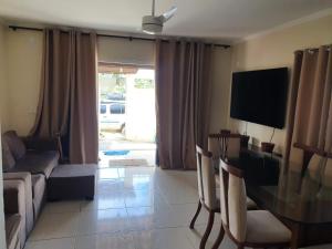 ein Wohnzimmer mit einer Couch und einem Tisch und einem Fernseher in der Unterkunft Casa Balneário in São Pedro da Aldeia