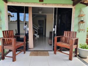 zwei Holzstühle auf der Veranda eines Hauses in der Unterkunft Casa Balneário in São Pedro da Aldeia