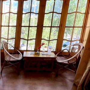 a room with two chairs and a table in front of a window at Hotel Namgyal Villa in Nubra