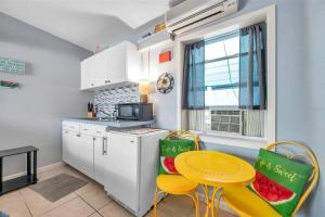 Wave condo في سانت بيتي بيتش: مطبخ به طاولة وكرسيان وطاولة صغيرة وطاولة صفراء