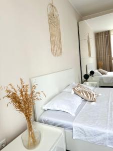 a white bedroom with a bed and a vase on a table at MoonLight Charming Shelter - spacious, 180º Balcony View in Oradea +11 photos