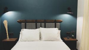 ein Bett mit weißen Kissen und einer blauen Wand in der Unterkunft Innwoods Hotel Alaverdi in Alawerdi
