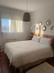 a bedroom with a large white bed and a window at V&B VACACIONAL in Suances +22 photos