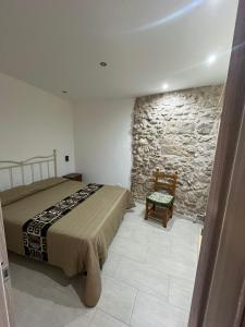 a bedroom with a bed and a stone wall at Le casette nel cortile in Sciacca
