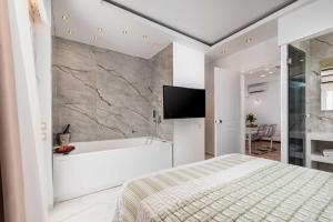 a bedroom with a bed and a tub and a television at Hotel Aeollos in Pefkochori