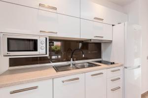 a white kitchen with a sink and a microwave at Hotel Aeollos in Pefkochori