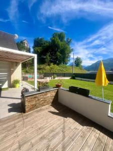 a backyard with a wooden deck with a yellow umbrella at Villa Coustete in Bôo-Silhen