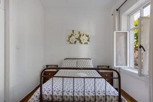 a bed in a white room with a window at Vivenda Barros in Sangalhos
