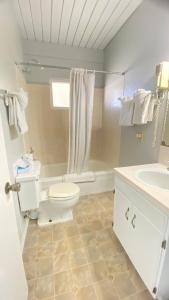 a white bathroom with a toilet and a sink at Ocean Shores Inn & Suites in Ocean Shores +119 photos