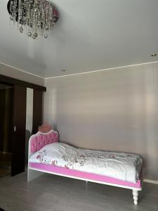 Una cama rosa en una habitación con una lámpara de araña. en Rakvere Apartments, en Narva