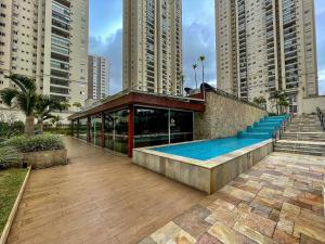 a building with a swimming pool next to tall buildings at 1606 - Luxo e Conforto na Cidade Maia in Guarulhos