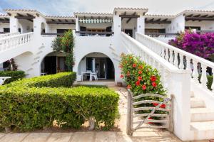 una casa blanca con flores en las escaleras en Costa arenal 29, en Arenal d'en Castell