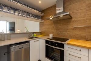 Una cocina con gabinetes blancos y un horno de estufa. en Costa arenal 29, en Arenal d'en Castell