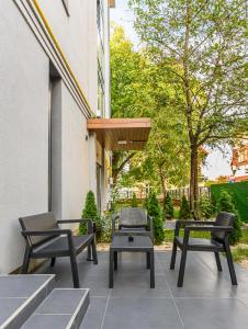 eine Terrasse mit 2 Stühlen, einem Tisch und Bänken in der Unterkunft KOA - Davino Aparthotel in Braşov