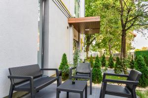 eine Gruppe von Stühlen und Tischen auf einer Terrasse in der Unterkunft KOA - Davino Aparthotel in Braşov + 52 Fotos