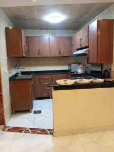 a kitchen with wooden cabinets and a counter top at ارقي شقه فندقيه بالمنصوره واطلاله كامله علي النيل in Ṭalkha