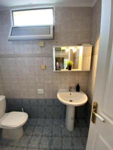 een badkamer met een wastafel, een toilet en een spiegel bij Cozy Maisonette Rebecca in Hanioti