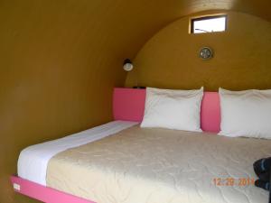 a bedroom with a bed with a pink and white headboard at Tubohotel in Tepoztlán