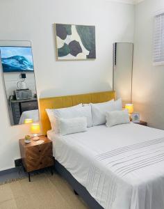 a bedroom with a large white bed and a mirror at Private Cosy Cottage on Pelican in Durban +10 photos