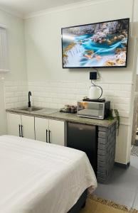 a bedroom with a bed and a tv on the wall at Private Cosy Cottage on Pelican in Durban