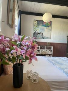 a vase with flowers on a table next to a bed at Charming rustic barn close to Tisvilde in Helsinge +15 photos