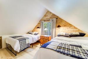 a attic bedroom with two beds and a window at Roscommon Chalet with Hot Tub Near Higgins Lake! in Roscommon