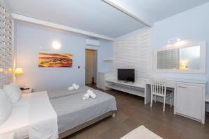 a bedroom with a bed and a desk and a television at Aktaion Resort in Gythio