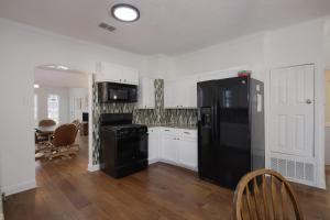 Una cocina con refrigerador negro y gabinetes blancos. en 126 Lucas Street, en San Antonio 2 fotos más