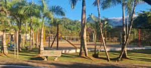 ein Park mit Palmen und einer Bank und einem Spielplatz in der Unterkunft Casa Espetacular Piscina Aquecida Ofuro Sauna in Caraguatatuba