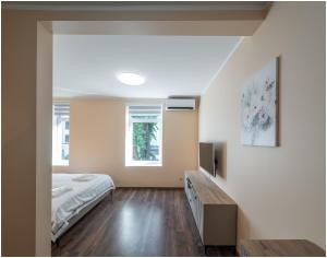 a bedroom with a bed and a dresser and two windows at Evena Travel Apartment in Rīga