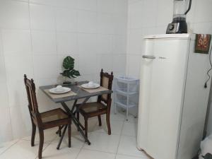 a kitchen with a table and a refrigerator at Apê 04 - Confortável e perto de tudo in Vitória da Conquista