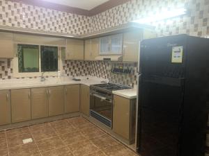 a kitchen with a black refrigerator and a stove at شقق لافندر in Sūq ath Thalut