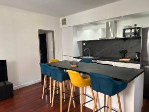 eine Küche mit einer schwarzen Theke und blauen Stühlen in der Unterkunft La maison du papé classé 3 etoiles in Bandol