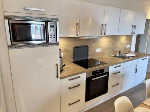 a kitchen with white cabinets and a microwave at FeWo Nordsee-Perle Meerblick - Horumersiel in Horumersiel